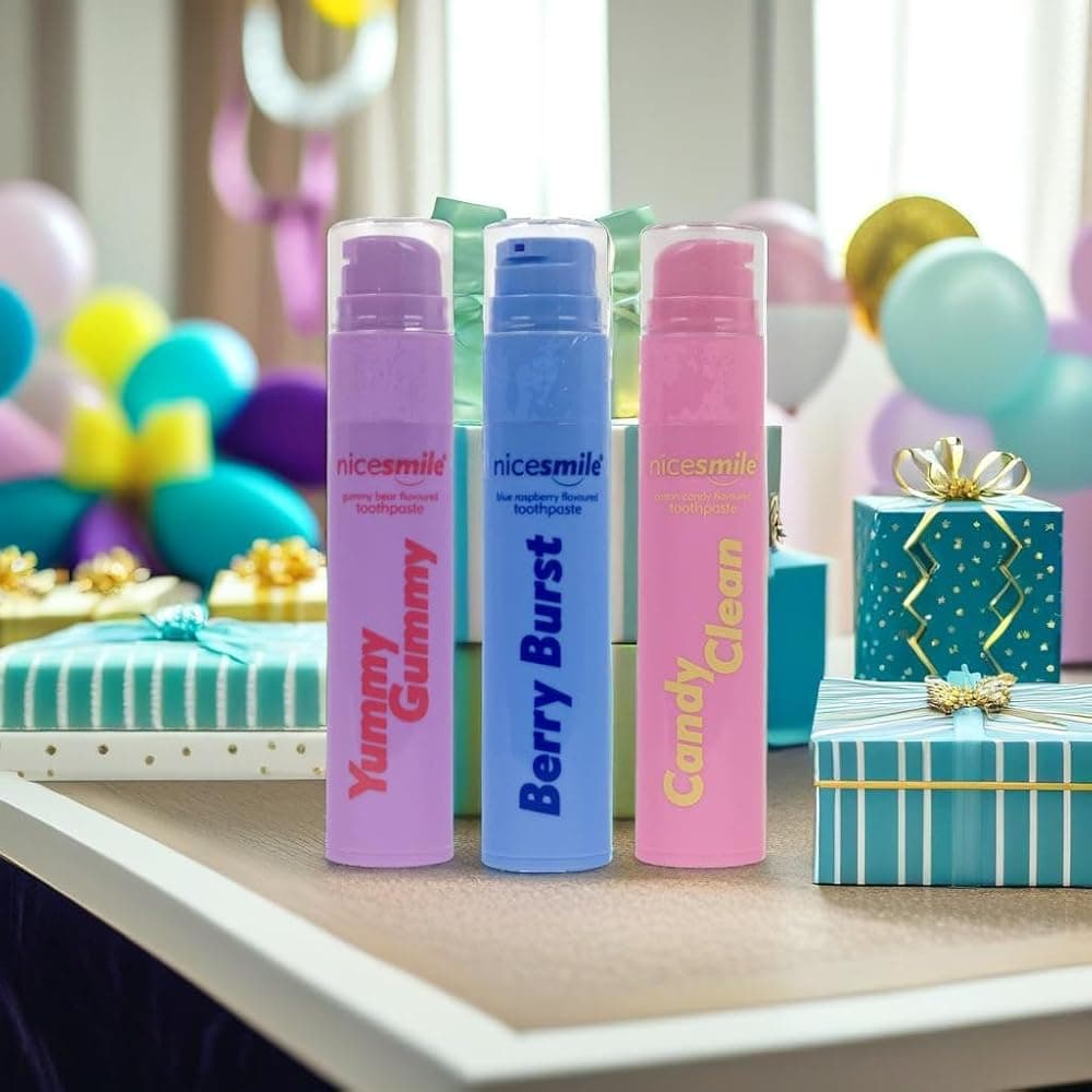 Nice Smile Yummy Gummy, Berry Burst and Candy Clean toothpaste on a table with party balloons and a gift box