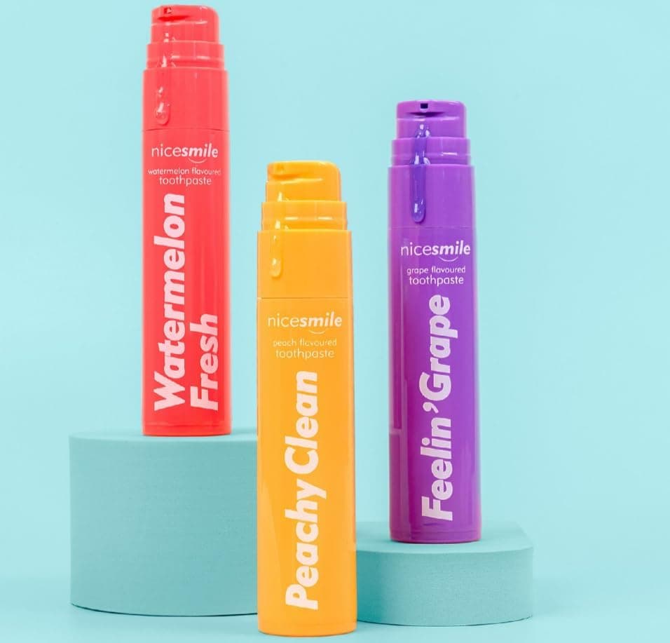 Nice Smile Watermelon Fresh, Peachy Clean and Feelin' Grape tubes on a teal podium